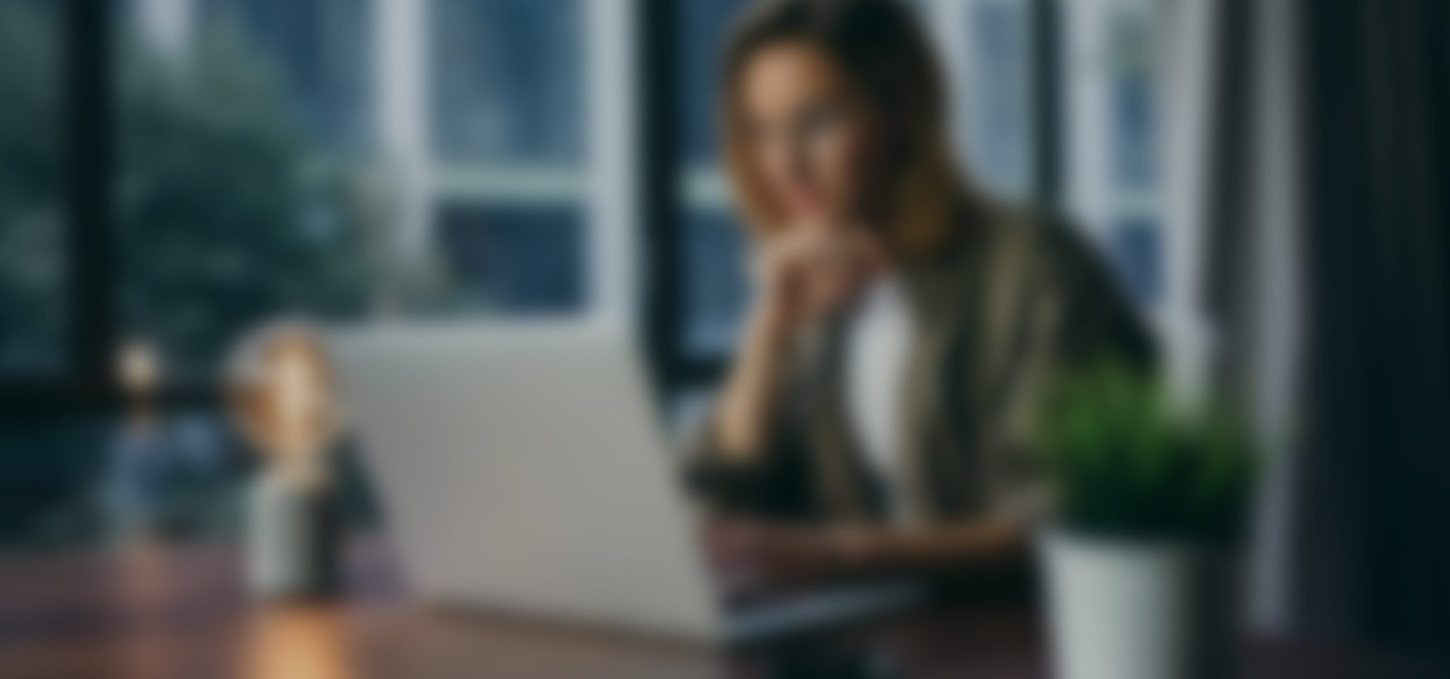 A Blurry Image Of A Woman Sitting At A Desk With Her Hand On Her Chin